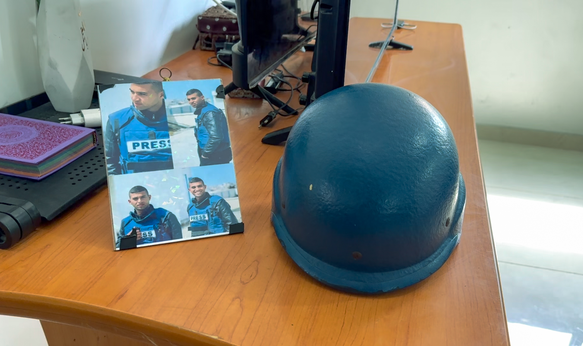 Hossam's helmet rests on a side table beside a photo collage of him